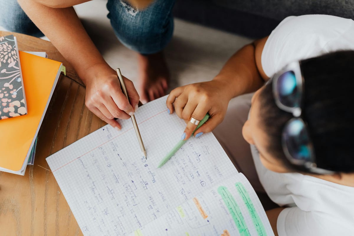 Une enseignante accompagne un enfant sur ses exercices de mathématiques